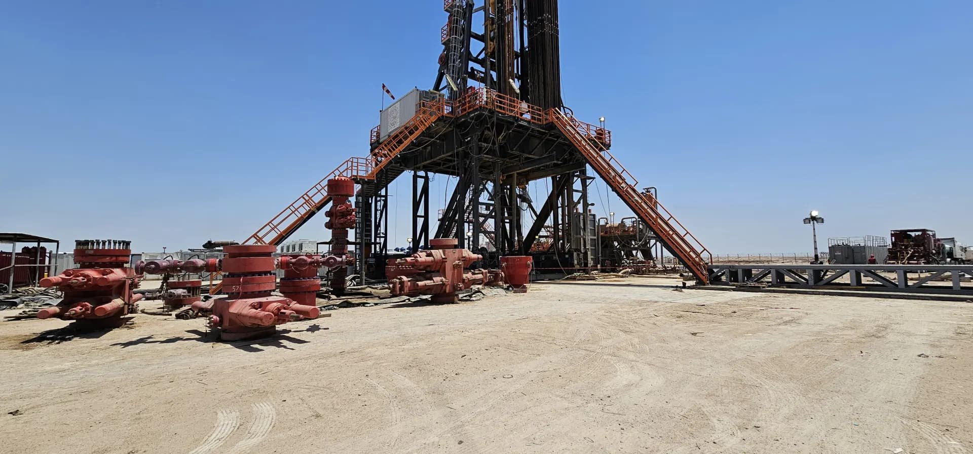 Drilling rig with wellhead equipment against a clear blue sky