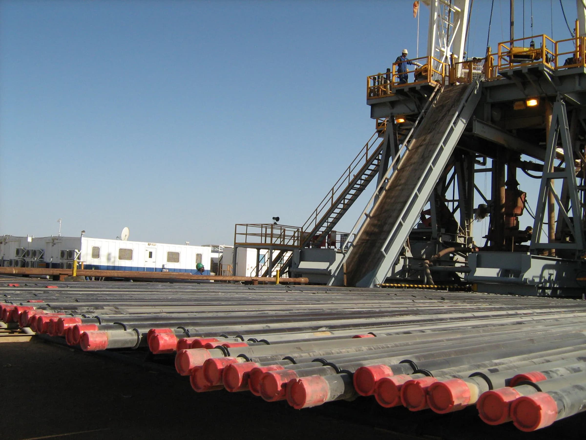 Tubulars racked on a drilling rig deck, rig substructure in the background